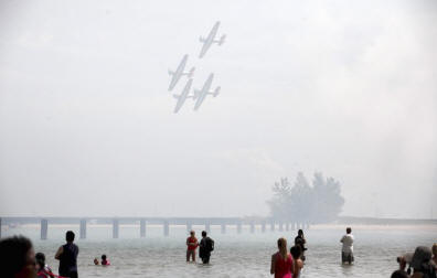 The Aeroshell Aerobatic Team flies over people swimming at the North Avenue beach during the 54th annual Air and Water Show in Chicago.